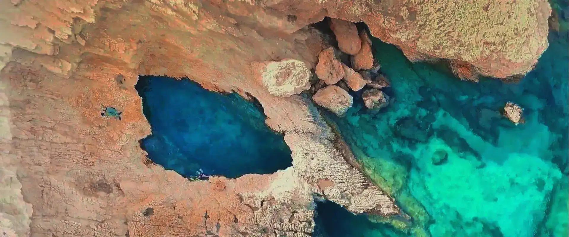 Aerial drone view of the Pisina natural pool in Koufonisia island with deep blue sea and rocky coastline